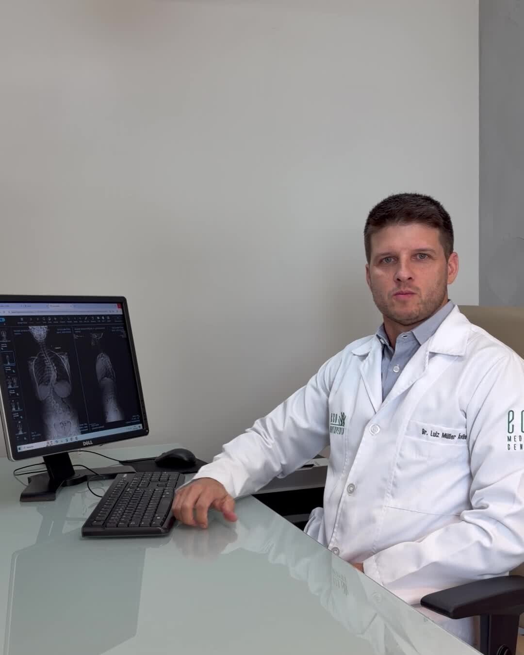 Dr. Luiz Müller Avila sentado à mesa do consultório, gravando um vídeo