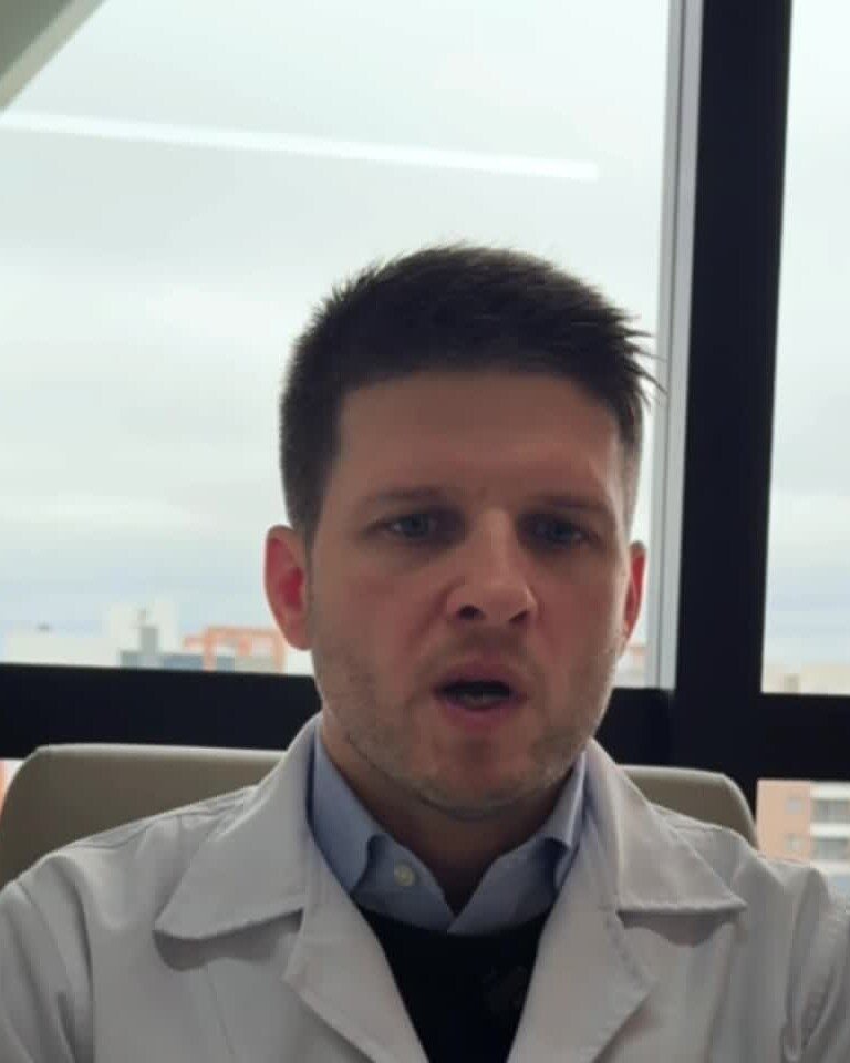 Dr. Luiz Müller Avila gravando um vídeo, diante de uma janela